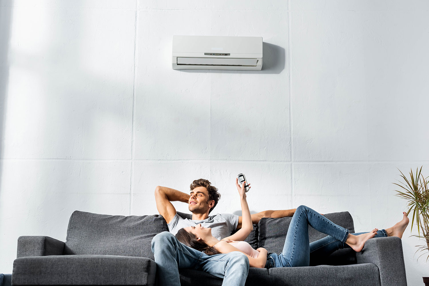 couple turning on ductless ac unit on wall