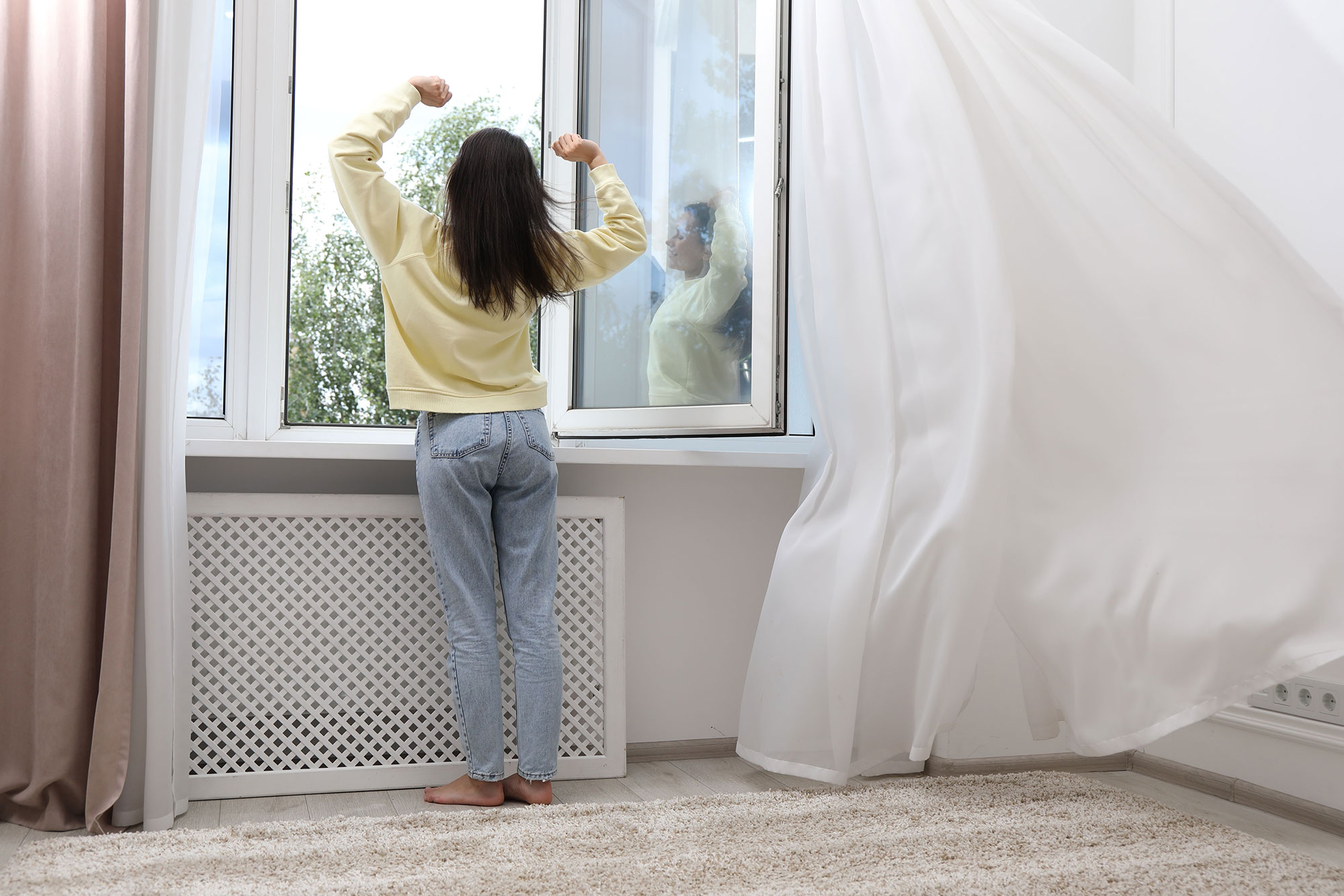 woman stretching in front of open window